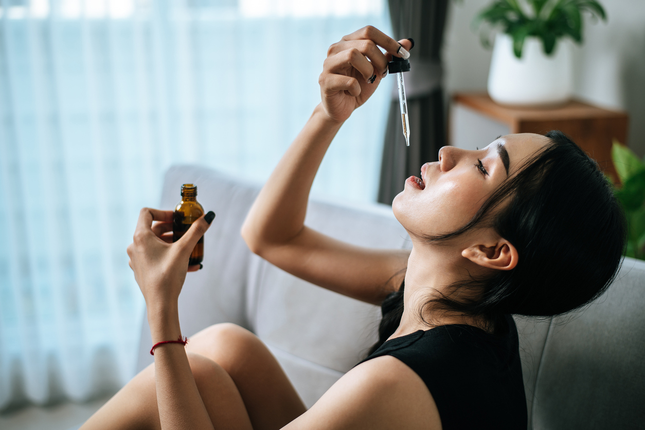 Young Asian woman dripping sublingual allergy drops
