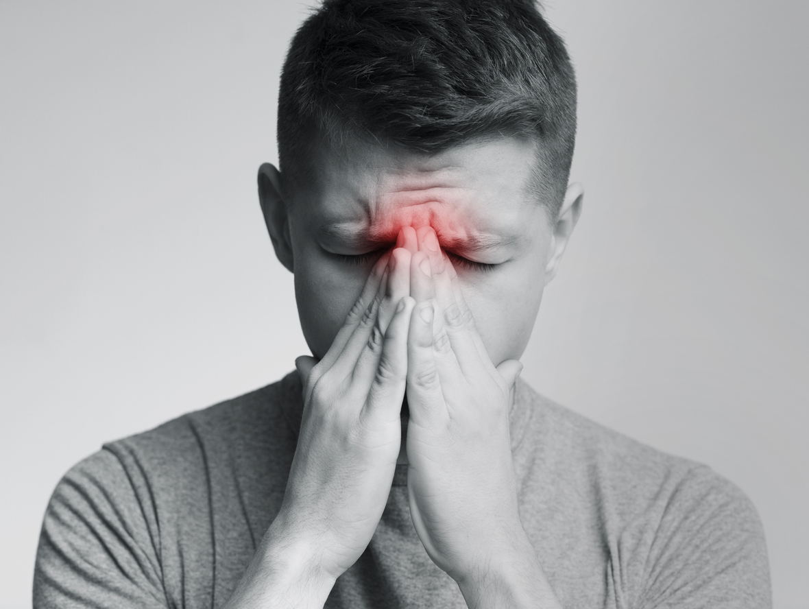 Man holding his nose in pain from chronic rhinosinusitis sinus pressure and congestion